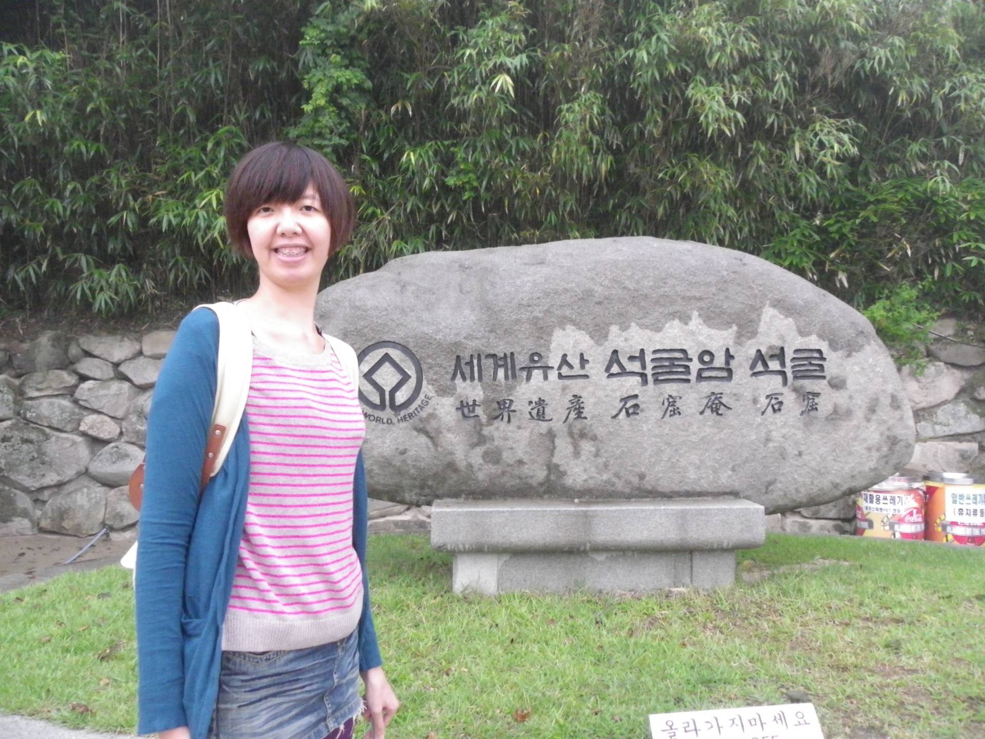 Image of Tzu-Han Chou in front of a Large Stone Statue.
